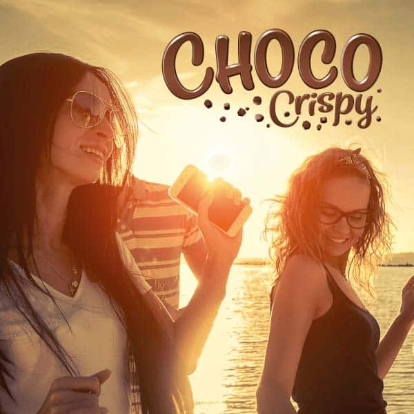 Dwie kobiety chodzą po plaży na tle zachodzącego słońca, na przodzie widnieje logo Choco Crispy