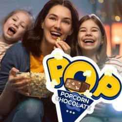 Woman watches something with two daughters and eats popcorn, on the front of the photo is the logotype: POP Popcorn & Chocolate